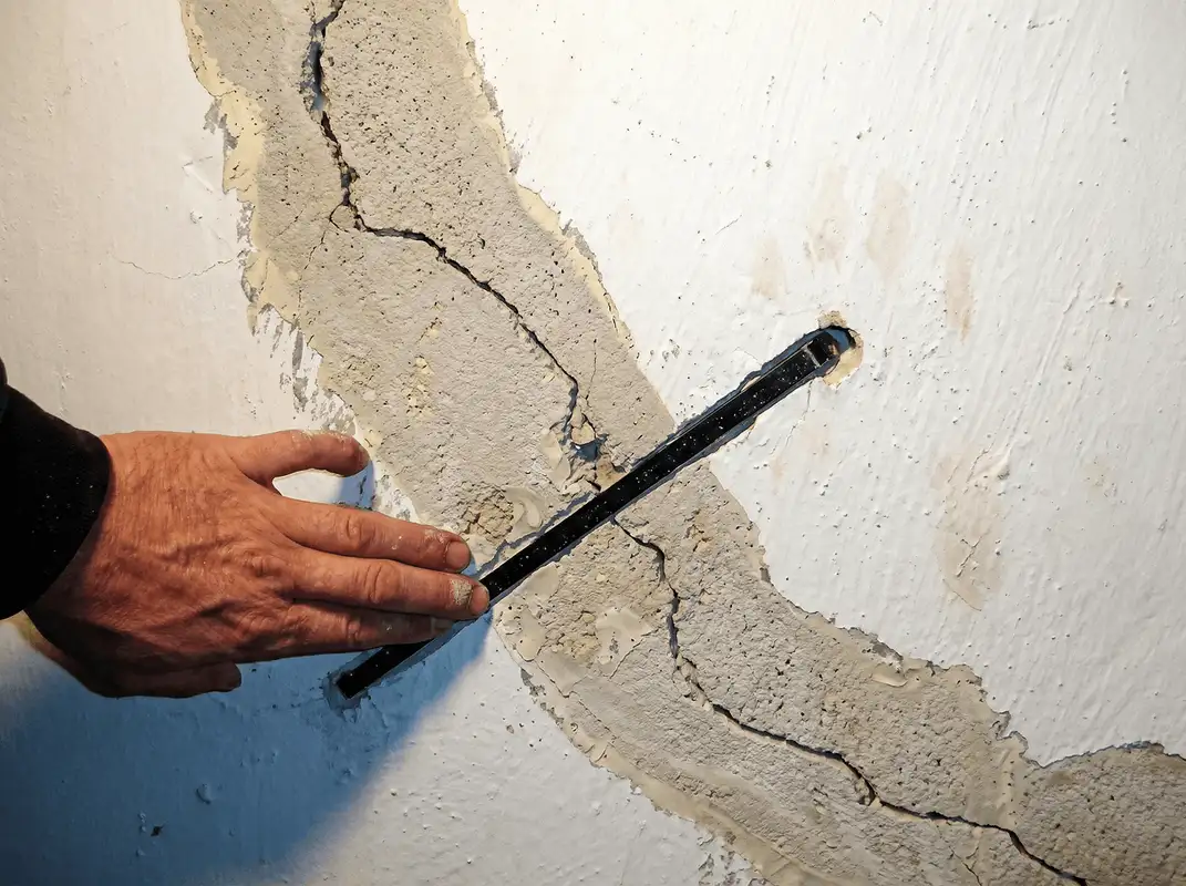 A wall with a large crack is being inspected by a professional in Columbus, OH