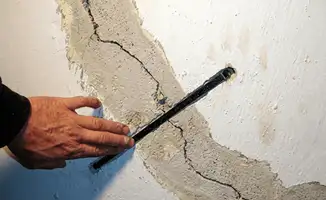 A wall with a large crack is being inspected by a professional in Columbus, OH